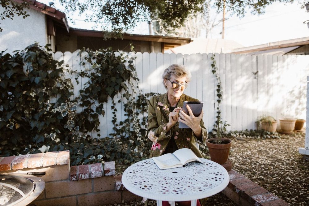 Femme senior consultant une tablette dans son jardin